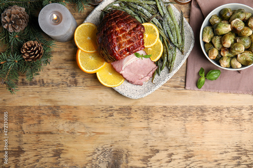 Festive flat lay composition with delicious ham on wooden table, space for text. Christmas dinner