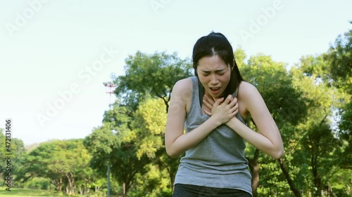 Woman exercising outdoors has chest pain, acute heart attack : Young woman suffering from heart disease holds her chest in agony.