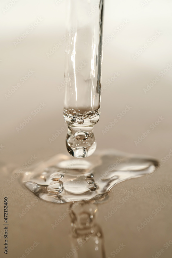 The texture of serum or oil with a pipette on a beige background. The texture of serum or oil with a pipette on a beige background.