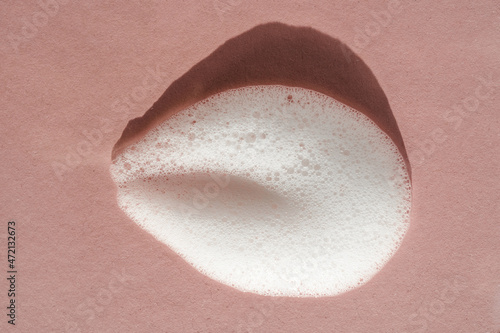 Texture of white foam on a pink background.