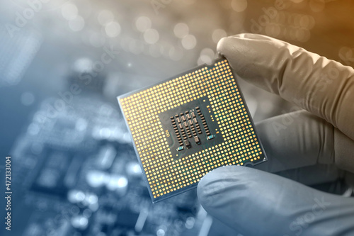 Canvas Print close up of gloved hand holding a microchip on electronic board background