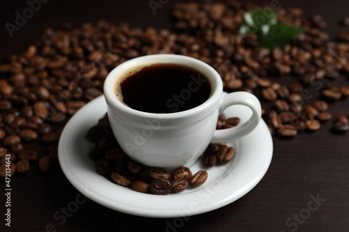 Cup of aromatic coffee and beans on wooden table
