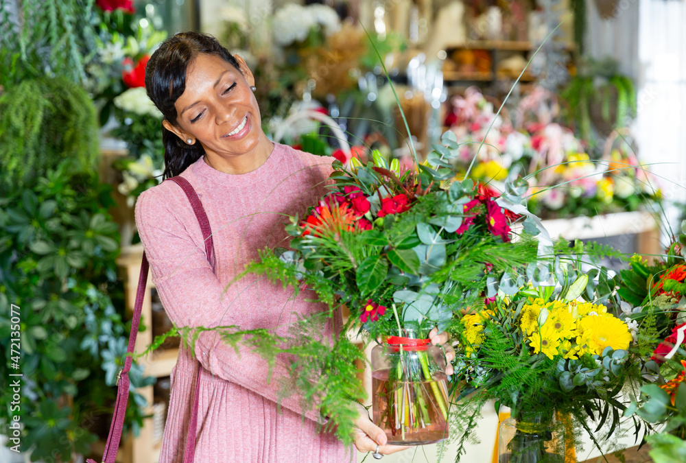 Happy female customer chooses bouquet of flowers at flower shop