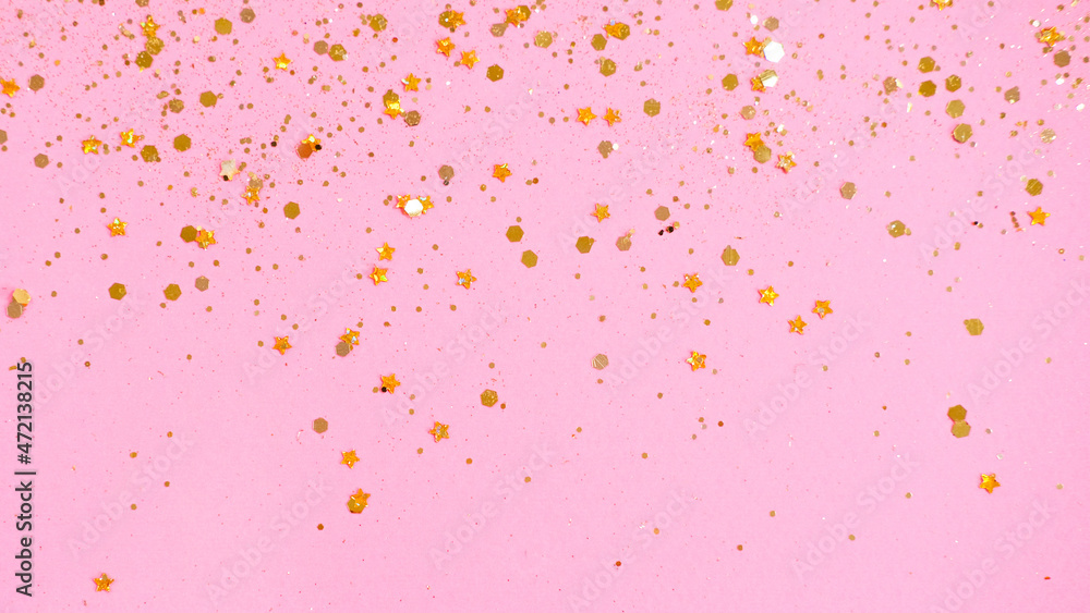 Festive Golden star sprinkles on pink background.