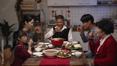 cheerful chinese family with mixed generation raising glasses to toast new year as they are gathering to have reunion dinner in celebration of spring festival at home