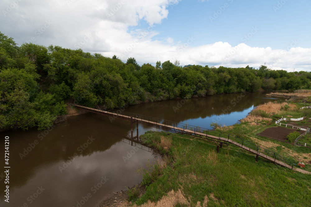 top view of a small wooden bridge over the river near the village near the forest