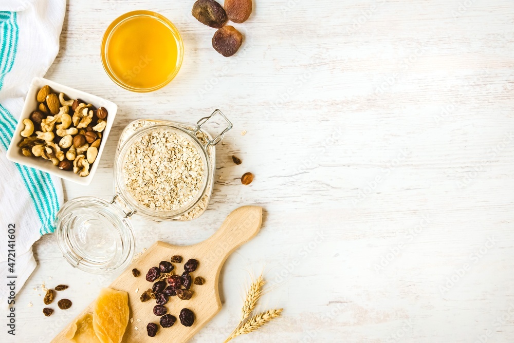 Top view of raw ingredients for homemade granola preparation - oats, nuts, honey and dried fruits. Healthy eating. Copy space.