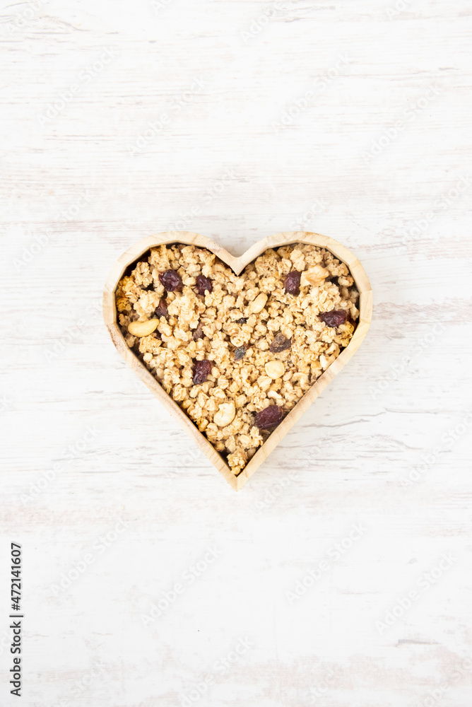 Top view of a heart shaped bow full of crunchy granola. Healthy eating concept.