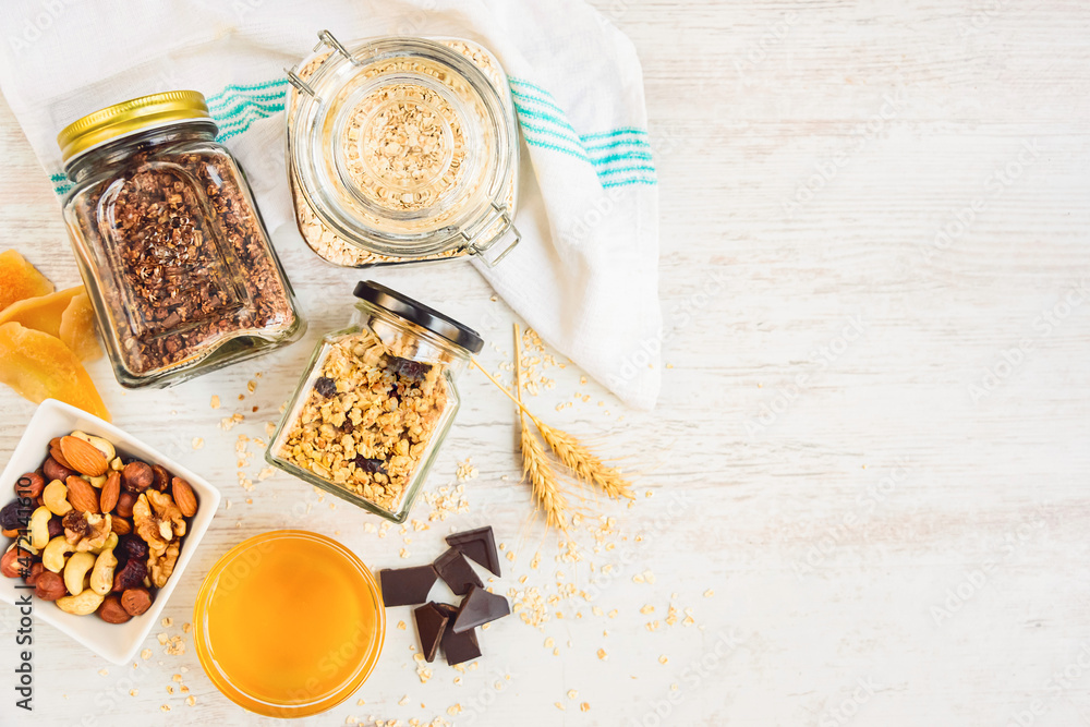 Top view of jars full of oats and various crunchy granola - plain, dried fruits, nuts and chocolate. Healthy eating concept. Copy space.