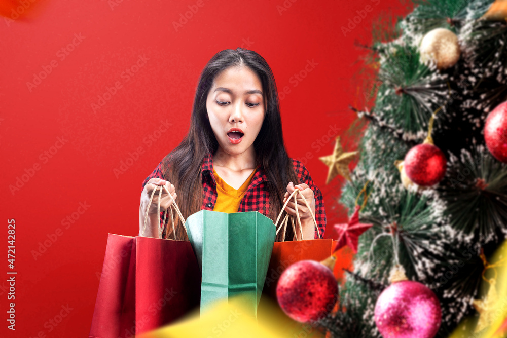 Decorated Christmas tree with Asian woman opening shopping bag Decorated Christmas tree with Asian woman opening shopping bag