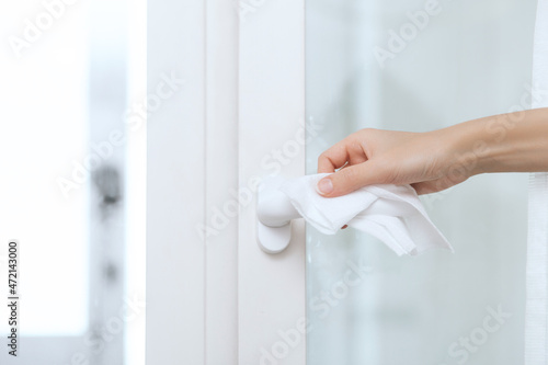Cleaning door handles with an antiseptic wet wipe and gloves. Woman hand using towel for cleaning home room door link. Sanitize surfaces prevention in hospital and public spaces against corona virus