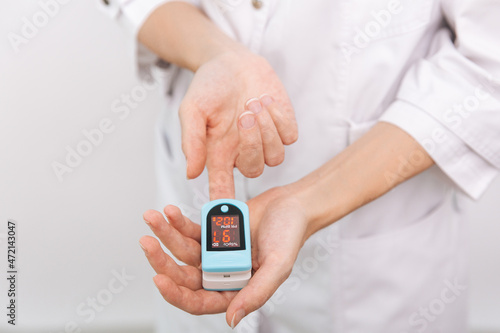 Pulse oximeter with hand of doctor isolated on white. The concept of portable digital device to measure person's oxygen saturation. Measuring oxygen saturation, pulse rate and oxygen levels