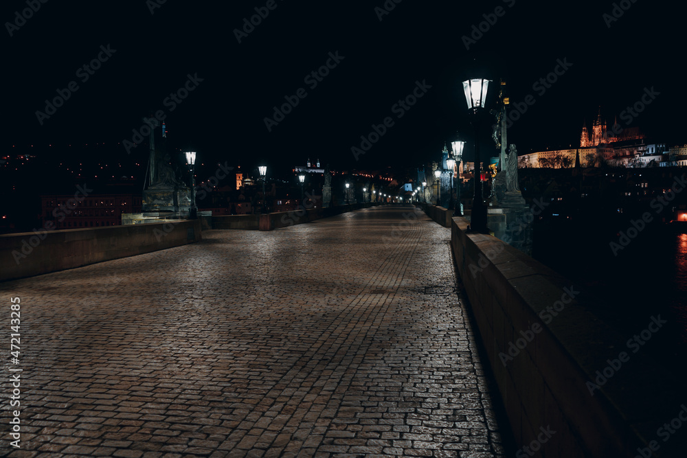 Fototapeta premium Street lights on the old stone Charles Bridge in the center of the city of Prague On the Vltava river at night and light from the street lights