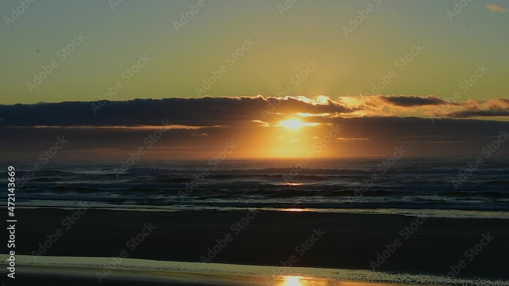 Dramatic view across a deserted beach with a stunning golden sunrise or sunset with a silhouetted 4x4 truck driving past with fishing gear Dramatic view across a deserted beach with a stunning golden sunrise or sunset with a silhouetted 4x4 truck driving past with fishing gear