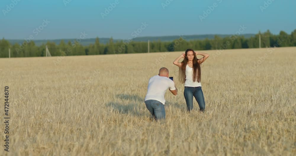 Happy girl posing on the phone, photo shoot in a wheat field. Young man takes a photo of a beautiful girl on a smartphone, the girl poses and smiles. 4k, ProRes Happy girl posing on the phone, photo shoot in a wheat field. Young man takes a photo of a beautiful girl on a smartphone, the girl poses and smiles. 4k, ProRes