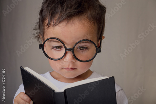 portrait of a little boy reading a black book