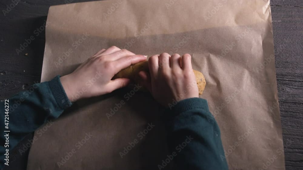 Young female child rolls baking dough on baking paper , rolling and preparing the dough , overhead shot Young female child rolls baking dough on baking paper , rolling and preparing the dough , overhead shot