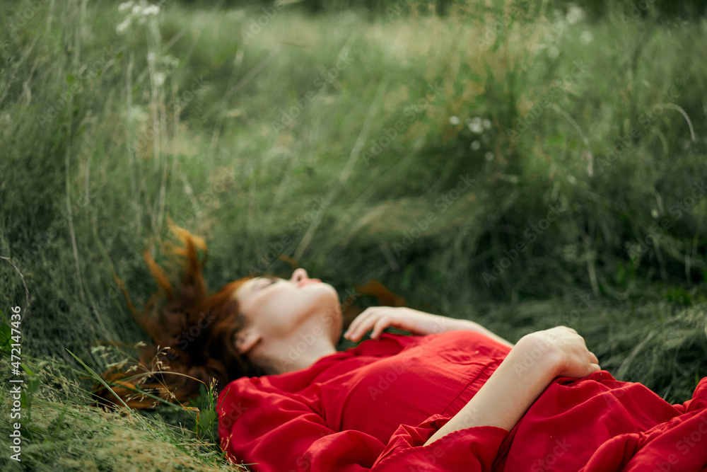 Naklejka premium pretty woman in red dress lies on the grass in the field nature fresh air