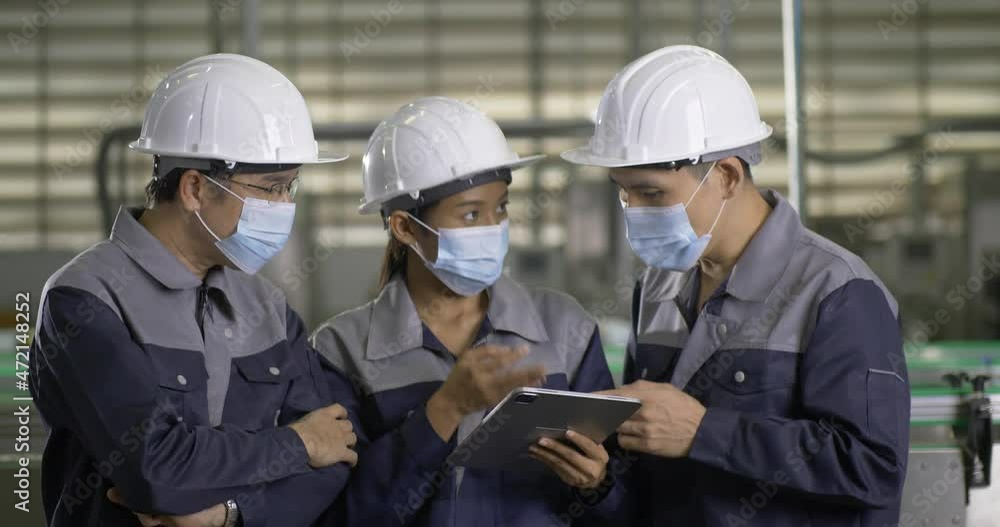 Group of engineer working at factory. They wearing mask while working together. They Work at the Heavy Industry Manufacturing Facility. Group of engineer working at factory. They wearing mask while working together. They Work at the Heavy Industry Manufacturing Facility.