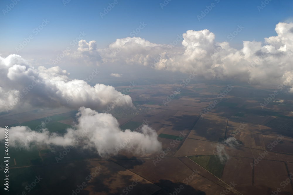 Obraz premium Aerial view from airplane window of white puffy clouds on bright sunny day