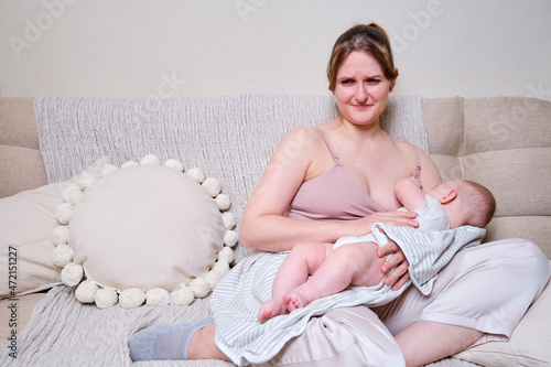 Pain and problems in a woman while breastfeeding a baby. Mother experiences discomfort while breastfeeding photo