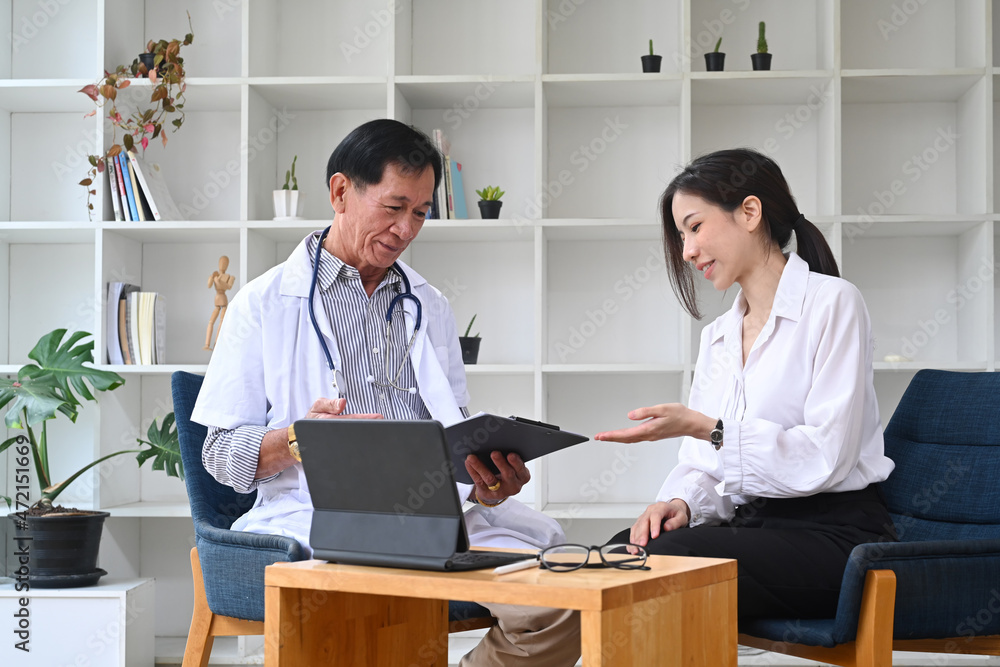 Mature doctor in white uniform consultation with young asian patient in hospital. Mature doctor in white uniform consultation with young asian patient in hospital.