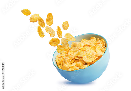 dry corn flakes isolate in a blue ceramic plate, part of the corn flakes is flying in the air. traditional cornflakes breakfast concept photo