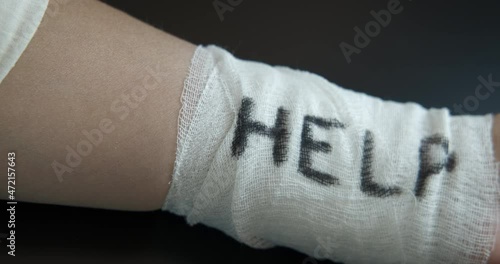 Suicide prevention. A view of a bandaged hand with word help because of suicide problems.