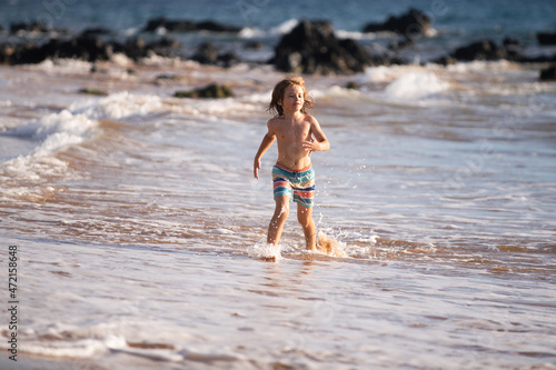 Child boy on the coast. Little kid playing in the ocean. Holidays on the sea. The child in waves.