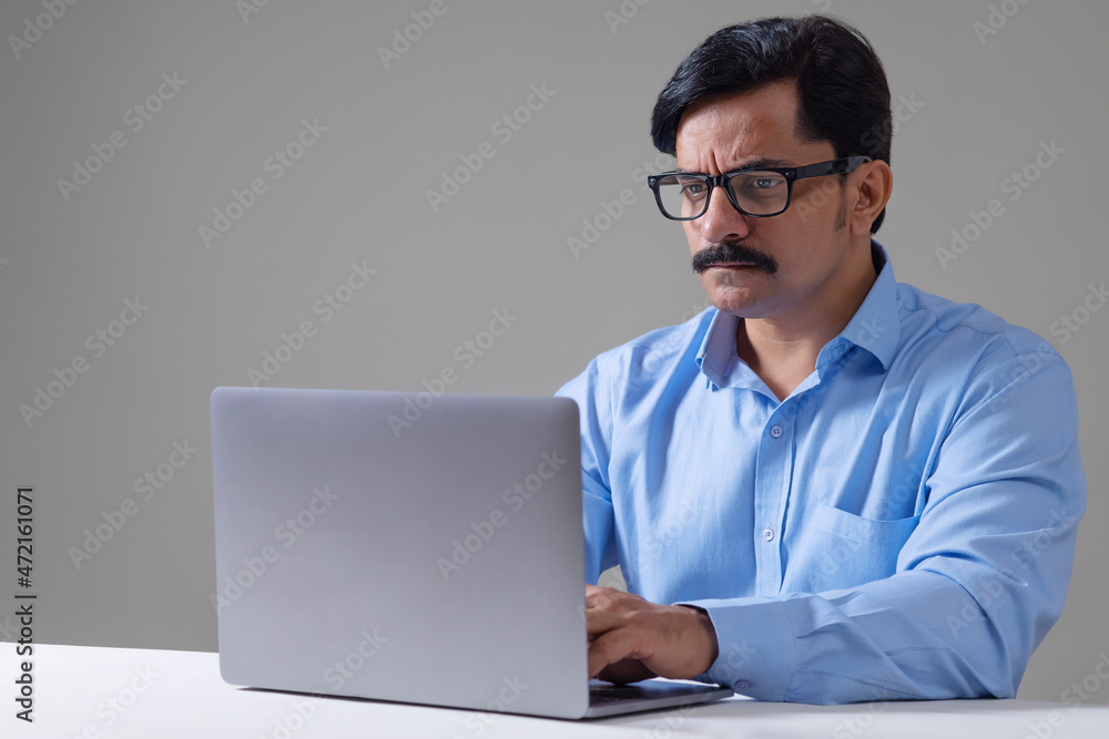 Man in formal dress doing office work using laptop