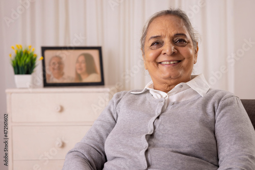Old sick woman looking at camera with smile at home