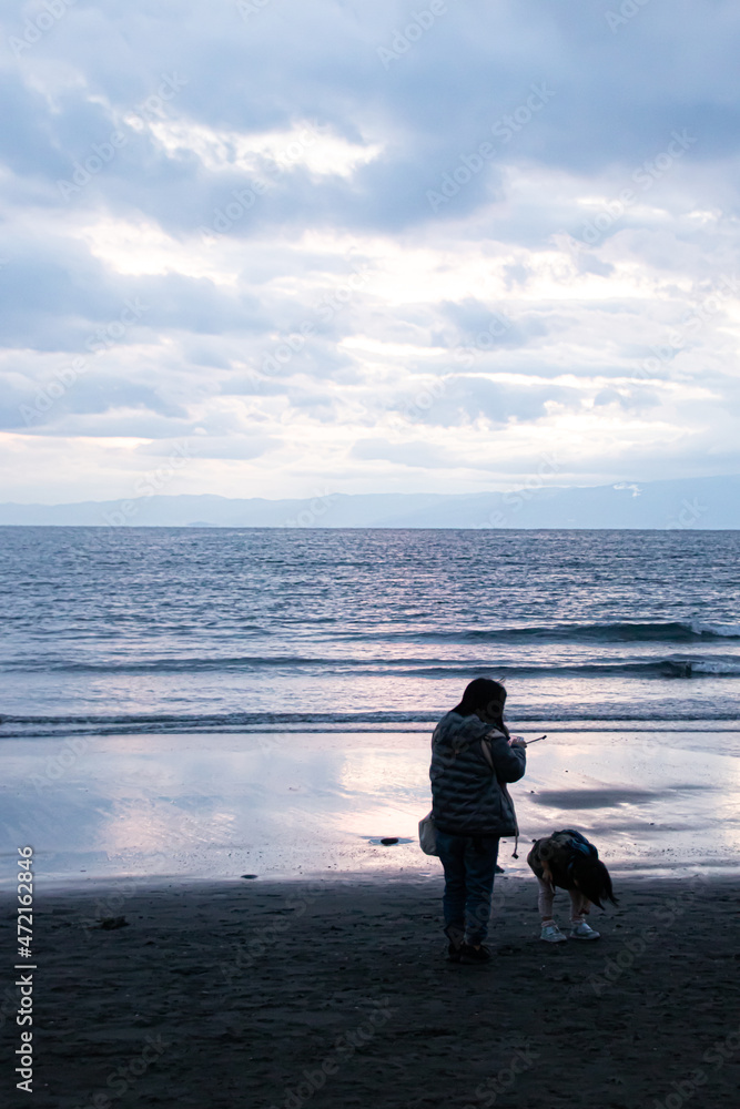 Naklejka premium 夕焼けの海を背景に映る女性と子供