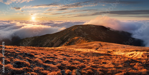 Fabulous sunset high in the mountains above the clouds. Aerial view of dramatic mountain landscape at dusk with fog and soft light. photo