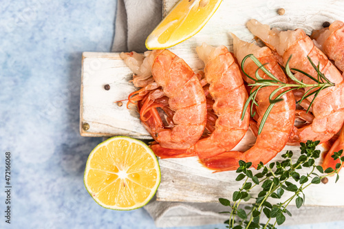 Raw Argentine shrimps on white wooden cutting board with lime, herbs and pepper. Seafood.