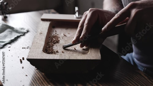 wood carving. a woodcarver processes a oak wood board with a chisel. woodworking process with hand tools in a carpentry workshop