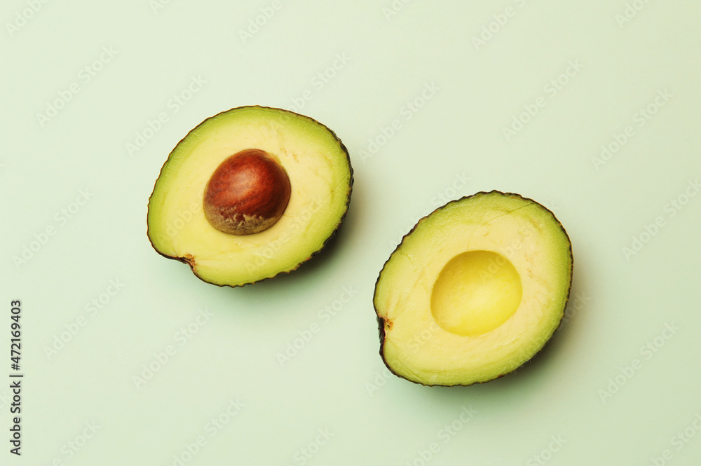 Avocado cut in half on soft green background