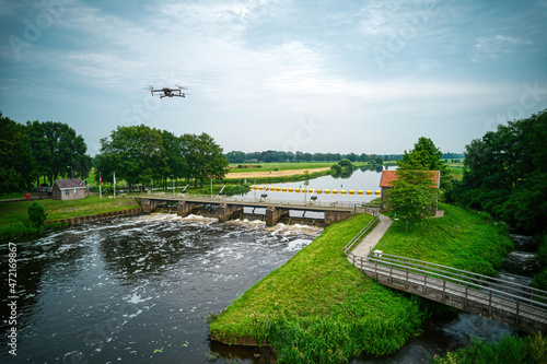 An aerial view with drone in the background above a weir in the river Vecht in the Netherlands. Downstream, Sluiswachtershuis next to the bridge. Fish pass, fish ladder. Overijssel Vecht