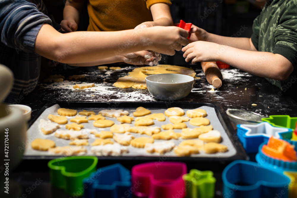 Children put cookies on a baking sheet. Cooking different forms of cookies for the holiday.