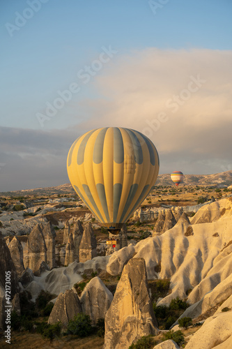 Amazing attraction - hot air balloons flying above unusual rocky landscape. Vertical photo