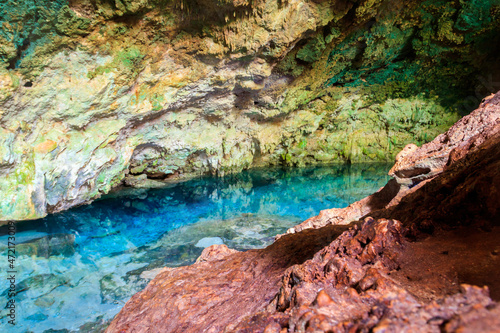 View of beautiful natural pool of crystal clear water formed in a rocky cave with stalagmites and stalagmites. Kuza cave in Zanzibar, Tanzania © olyasolodenko