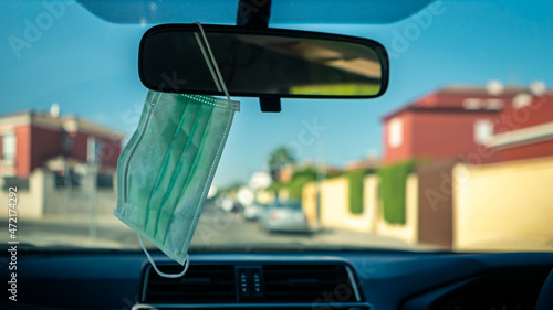 Fototapeta Naklejka Na Ścianę i Meble -  Hygienic masks hanging on rearview mirror inside of car whit sunlight. Covid19