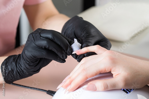 Manicurist treats the client s nail with a degreasing liquid to prepare nails for manicure  to remove the sticky layer.