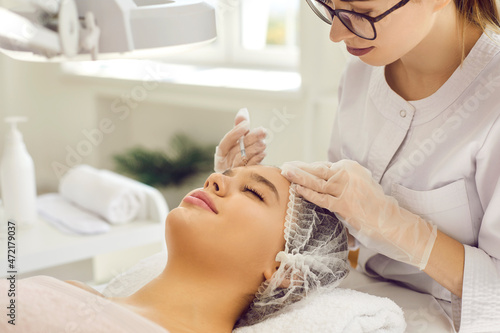 Beautician doctor make facial botox injection to woman client in aesthetic medicine clinic. Cosmetologist do face lifting procedures to female. Antiaging treatment. Skincare  cosmetology concept.