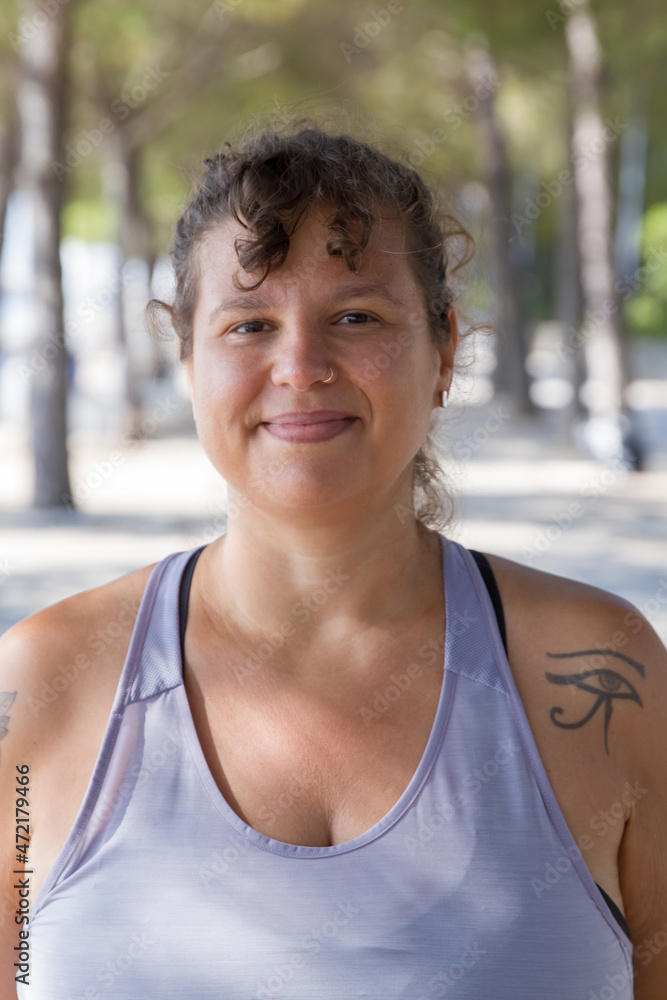 Portrait of smiling woman with curly bangs. Chubby woman in blue top with pierced nose looking happily at camera. Sport, body positive concept Portrait of smiling woman with curly bangs. Chubby woman in blue top with pierced nose looking happily at camera. Sport, body positive concept