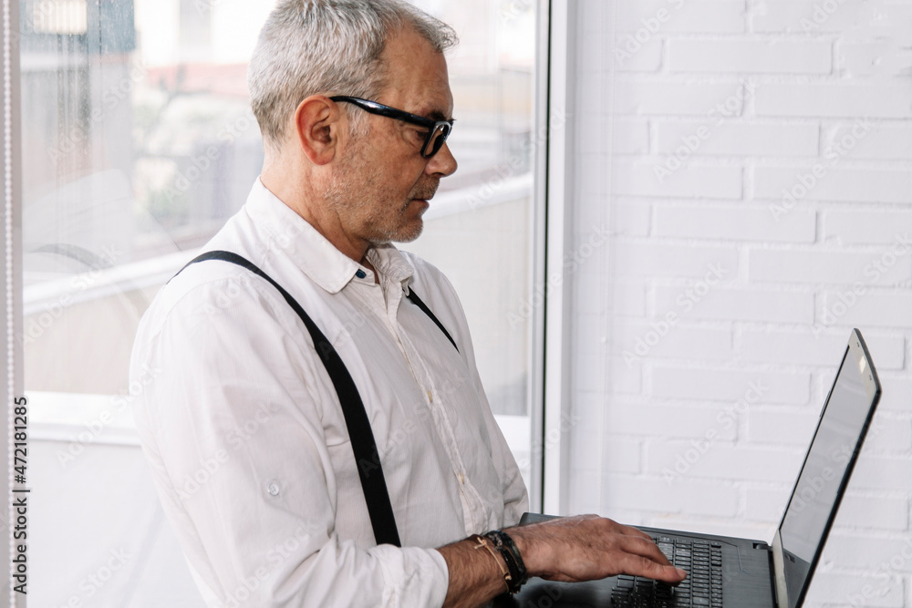 mature man with laptop in office or at home