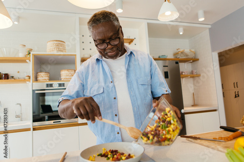Senior African man standing in the kitchen and preparing a healthy dinner.
