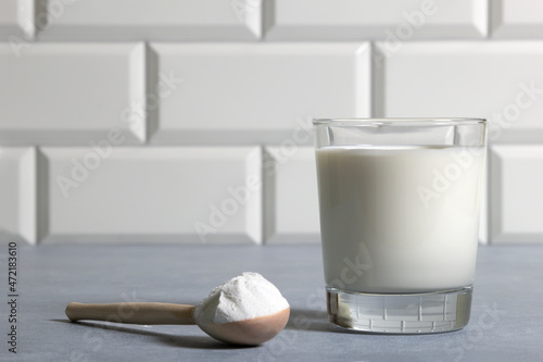 Glass of milk and full fat powdered milk in wooden spoon in kitchen