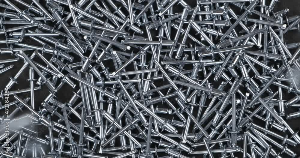 Aluminum rivets fall onto a rotating pile of metal rivets. Rotating rivets. Top view. Close-up. Aluminum rivets fall onto a rotating pile of metal rivets. Rotating rivets. Top view. Close-up.