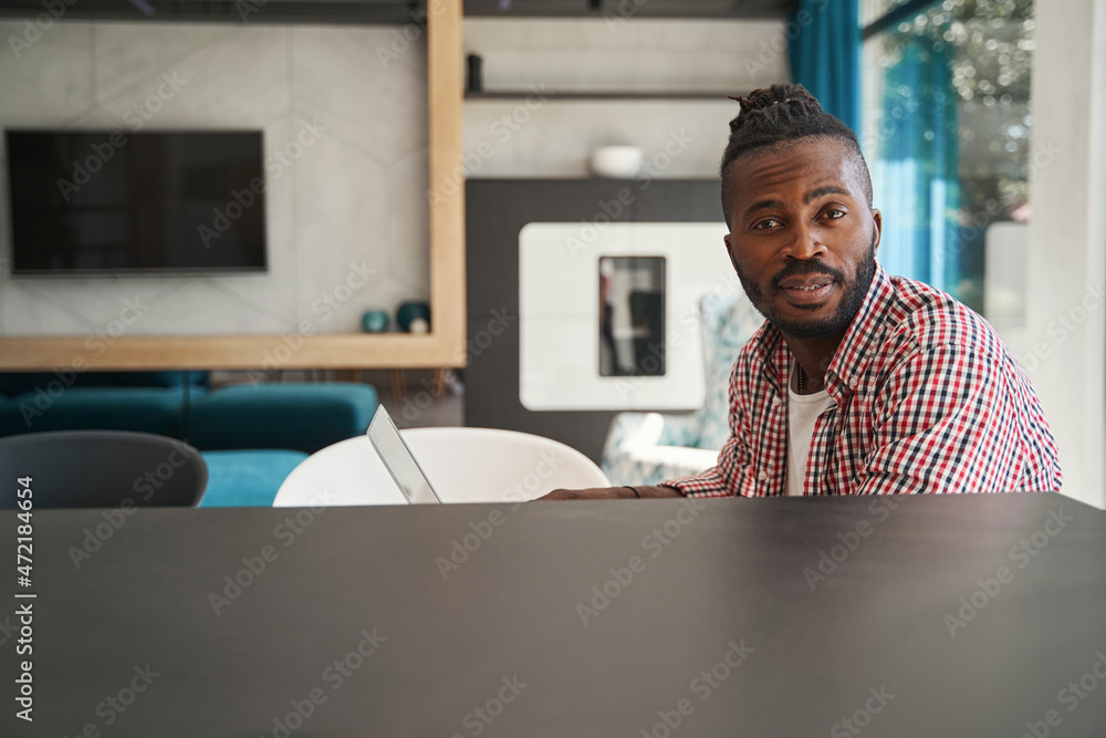 Fototapeta premium Tranquil African American male freelancer sitting at laptop