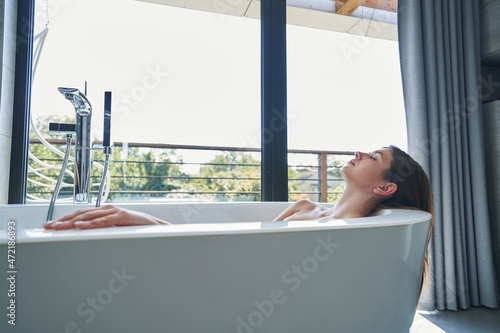 Fotografia Serene woman with eyes closed lying in bath
